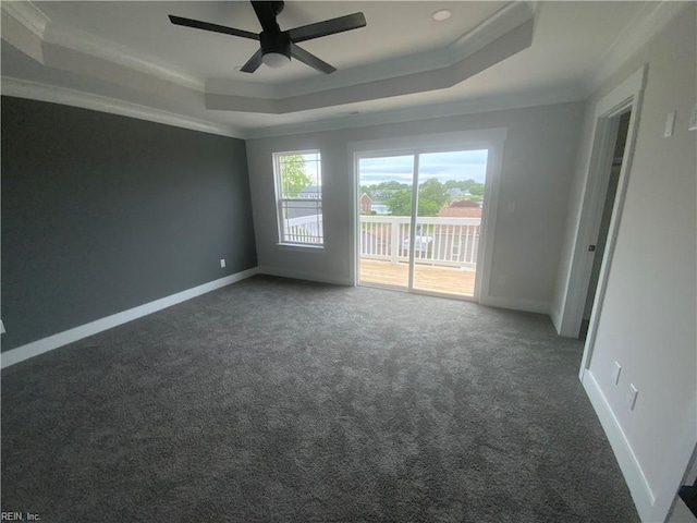 spare room with a raised ceiling, ornamental molding, carpet flooring, a ceiling fan, and baseboards