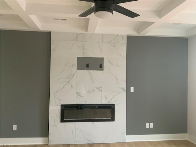 detailed view of a fireplace, coffered ceiling, a ceiling fan, beam ceiling, and wood finished floors
