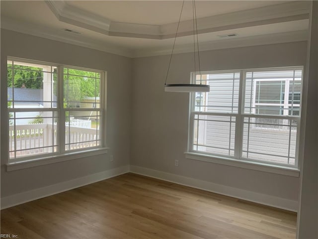 spare room featuring ornamental molding, a raised ceiling, light wood-style floors, and baseboards