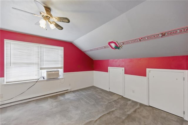 additional living space with vaulted ceiling, a baseboard heating unit, ceiling fan, carpet floors, and wainscoting