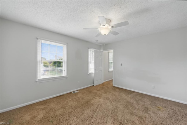unfurnished room featuring carpet flooring, ceiling fan, baseboards, and a textured ceiling