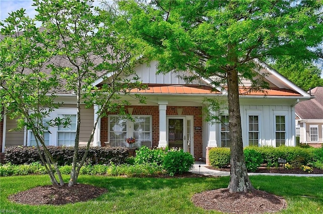 view of front facade featuring board and batten siding, brick siding, a front lawn, and a porch