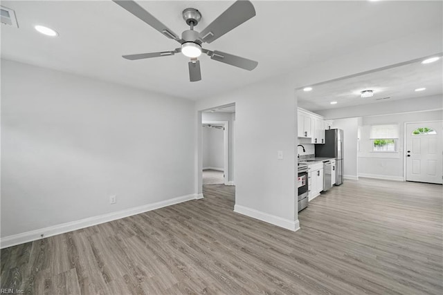 unfurnished living room featuring recessed lighting, baseboards, light wood finished floors, and a sink