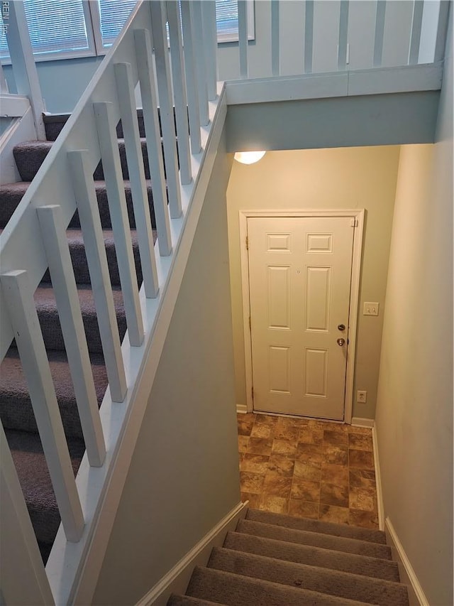 stairway featuring baseboards and stone finish flooring