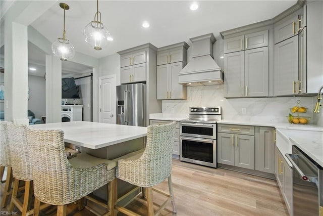 kitchen with appliances with stainless steel finishes, gray cabinets, premium range hood, tasteful backsplash, and recessed lighting