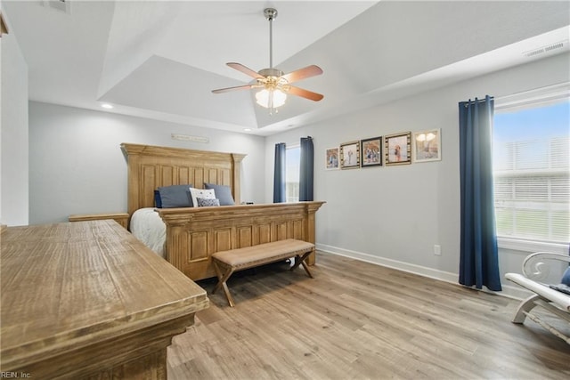 bedroom featuring light wood-style floors, baseboards, a ceiling fan, a tray ceiling, and recessed lighting