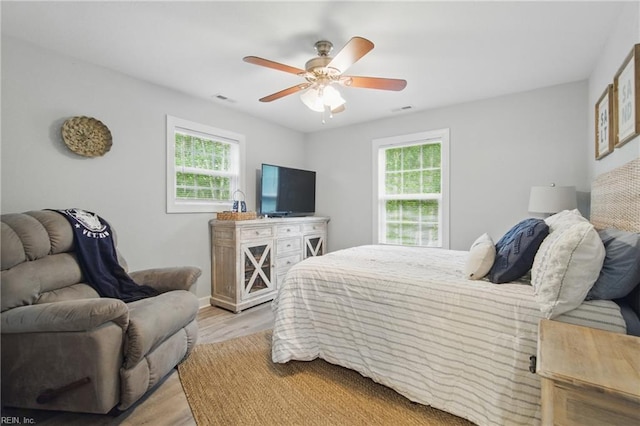 bedroom featuring multiple windows, light wood-type flooring, ceiling fan, and baseboards