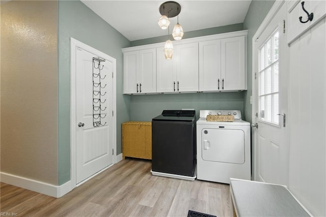 laundry area with separate washer and dryer, light wood-style flooring, cabinet space, and baseboards