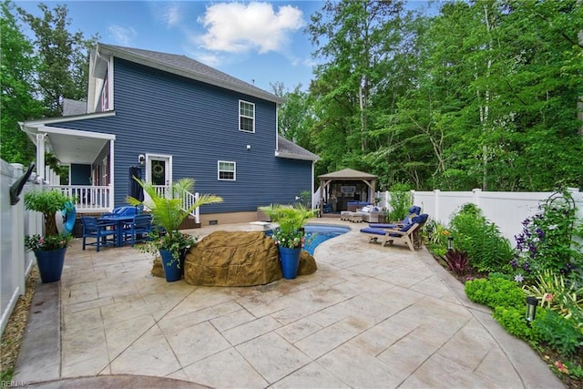 rear view of house with a gazebo, a patio, a fenced backyard, outdoor dining space, and an outdoor hangout area