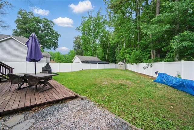 view of yard with outdoor dining area, a deck, a storage shed, and an outbuilding