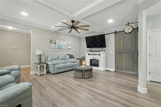 living area featuring coffered ceiling, light wood-style flooring, baseboards, a barn door, and a ceiling fan