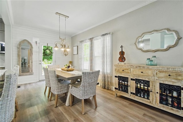 dining room featuring wood finished floors, a chandelier, and ornamental molding