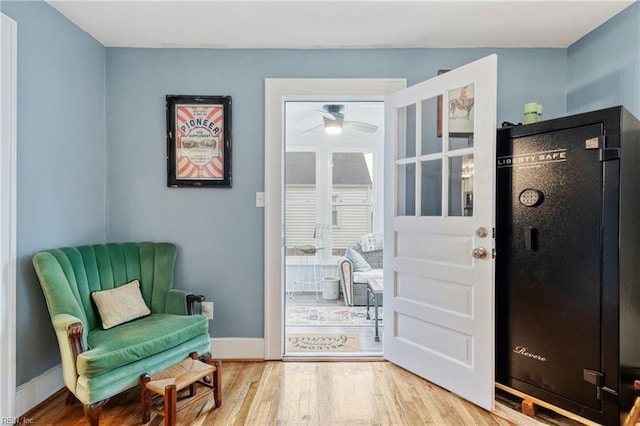 living area with wood finished floors, a ceiling fan, and baseboards