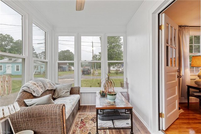 sunroom / solarium featuring wood finished floors, plenty of natural light, and ornamental molding