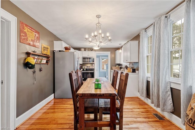 dining area featuring a chandelier, light wood-style flooring, and baseboards