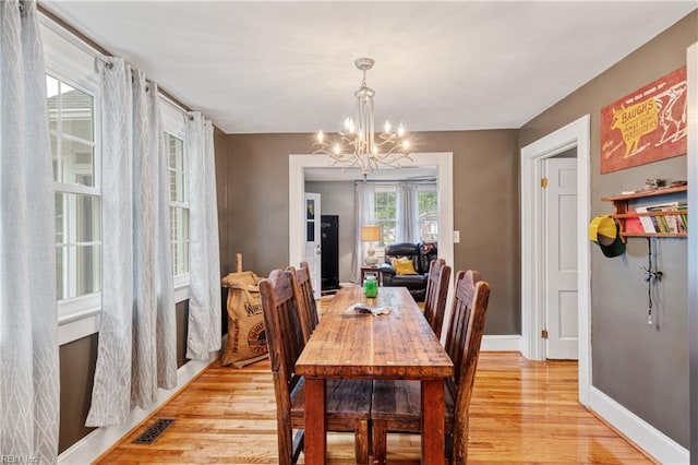 dining space featuring light wood-style floors, a chandelier, and baseboards