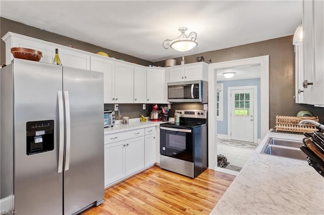 kitchen with appliances with stainless steel finishes, white cabinets, light countertops, and a sink