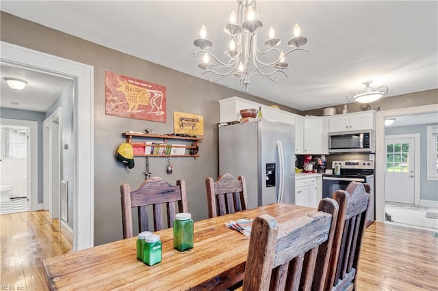 dining area with light wood-style floors, a chandelier, and baseboards
