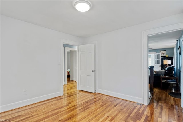 empty room featuring light wood-type flooring and baseboards