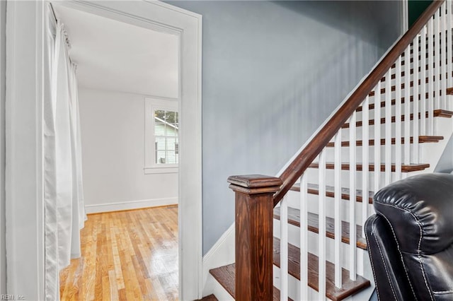 staircase featuring wood finished floors and baseboards