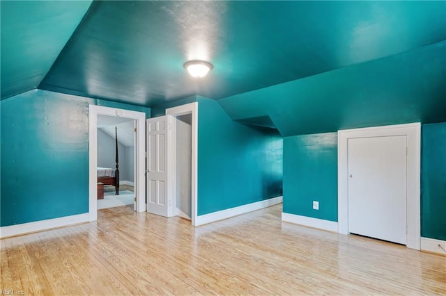 additional living space featuring wood finished floors, baseboards, and lofted ceiling