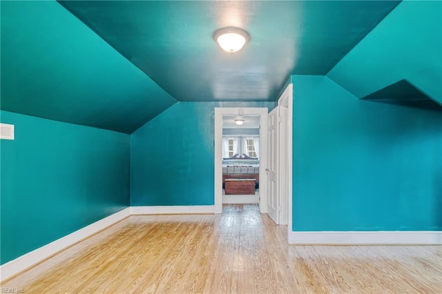 additional living space featuring baseboards, wood finished floors, and lofted ceiling
