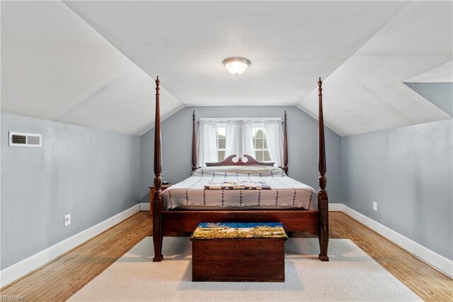 bedroom featuring wood finished floors, vaulted ceiling, and baseboards