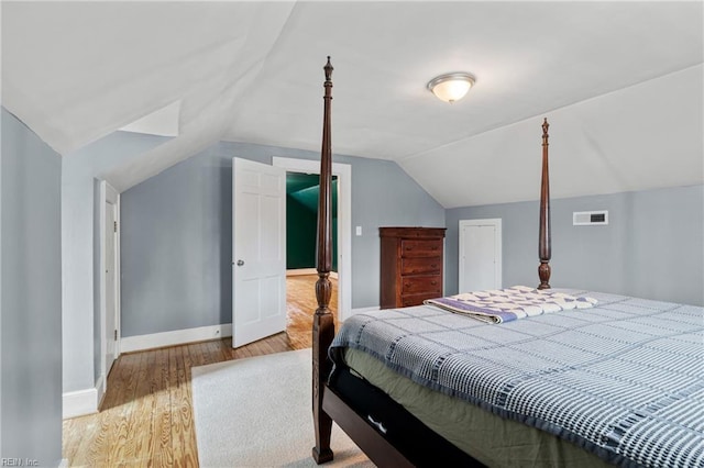 bedroom featuring wood finished floors, lofted ceiling, baseboards, and a closet