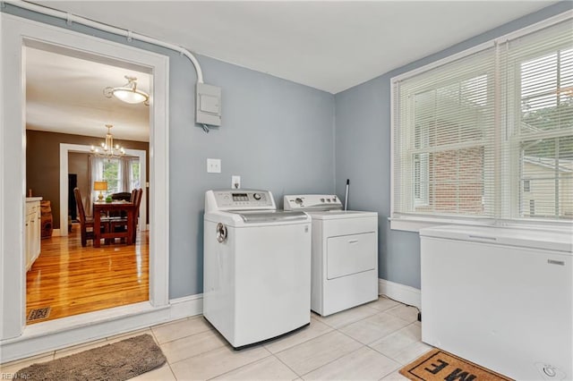 clothes washing area featuring washing machine and clothes dryer, a chandelier, baseboards, and light tile patterned flooring