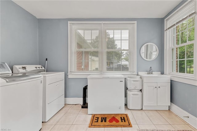 laundry room with washing machine and clothes dryer, light tile patterned floors, cabinet space, and baseboards