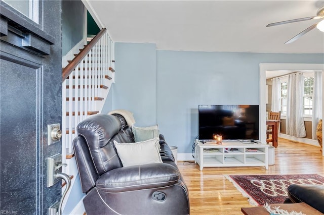 living room with ceiling fan, wood finished floors, stairway, and baseboards