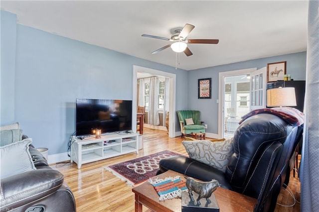 living area featuring a ceiling fan, baseboards, and wood finished floors