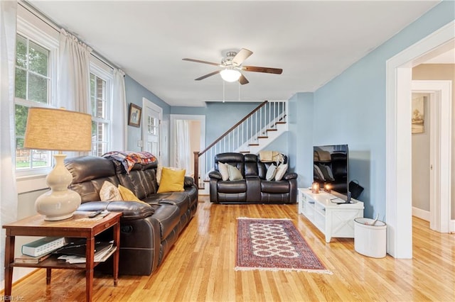living room with wood finished floors, stairway, a ceiling fan, and baseboards