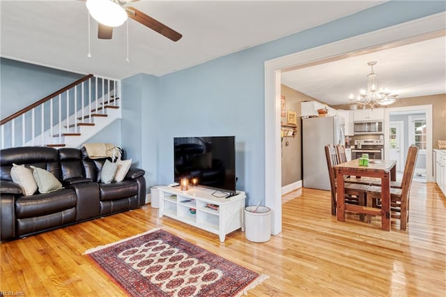 living area featuring light wood-style floors, a chandelier, stairs, and a ceiling fan