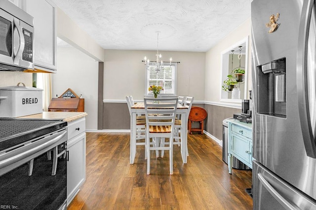 kitchen featuring appliances with stainless steel finishes, dark wood-style flooring, a chandelier, light countertops, and a textured ceiling