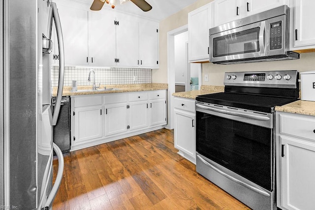kitchen with appliances with stainless steel finishes, a sink, white cabinets, and dark wood finished floors