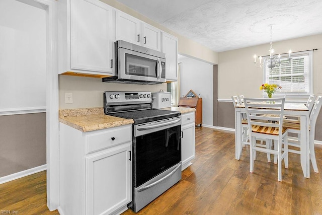 kitchen with stainless steel appliances, baseboards, a chandelier, dark wood finished floors, and a textured ceiling