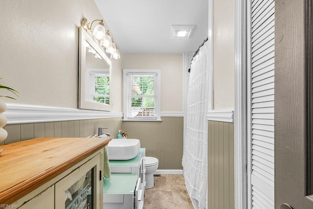 bathroom featuring vanity, wainscoting, and toilet