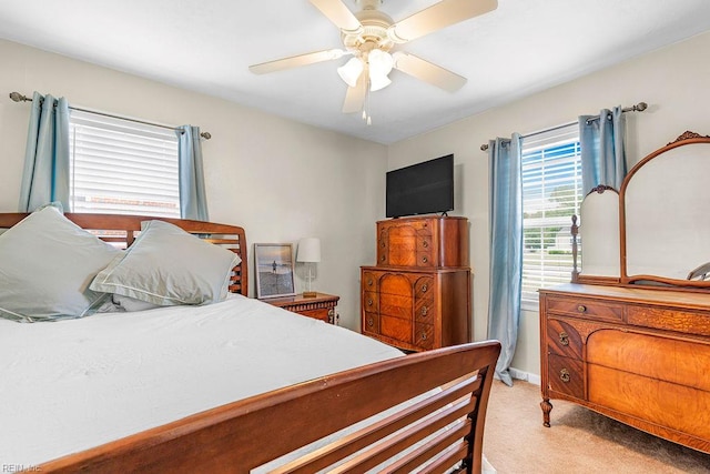 bedroom featuring light carpet, a ceiling fan, and baseboards