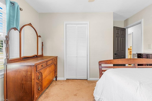bedroom featuring light colored carpet, baseboards, and a closet