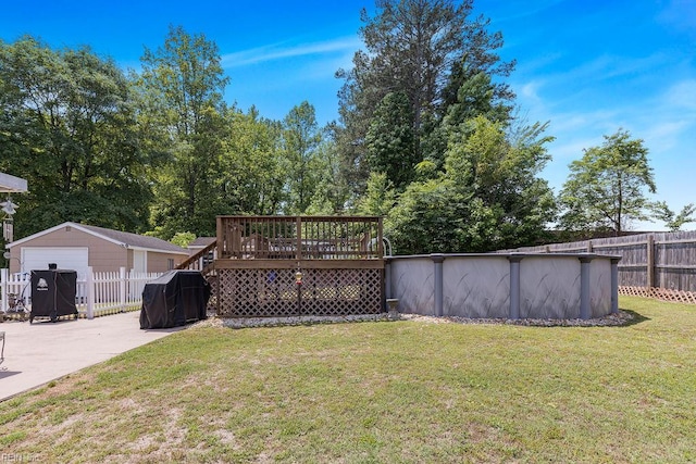 view of yard with a deck, a garage, an outdoor structure, driveway, and a patio area