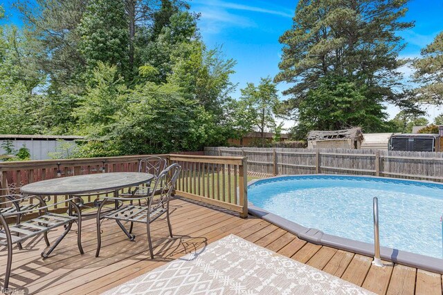 view of pool with a fenced backyard, a wooden deck, and outdoor dining space