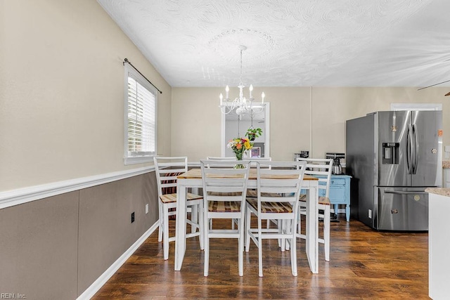 dining space featuring a chandelier, dark wood finished floors, and a textured ceiling