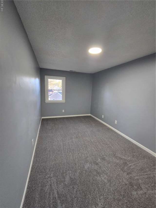 carpeted empty room featuring baseboards and a textured ceiling