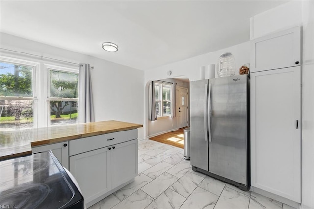 7811 Nesbitt Dr, Norfolk, VA 23505 - kitchen with freestanding refrigerator, butcher block counters, light marble finish floors, arched walkways, and black electric range oven