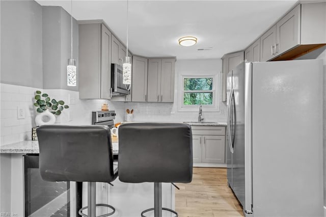 1233 25th St, Newport News, VA 23607 - kitchen with gray cabinetry, appliances with stainless steel finishes, a sink, light wood-style floors, and light stone counters