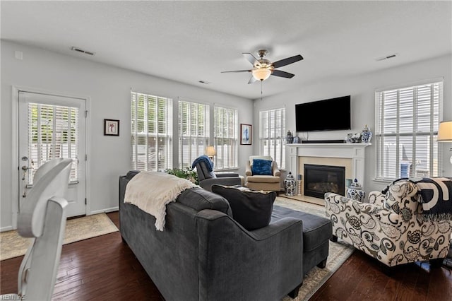 living room with ceiling fan, dark wood-style floors, a glass covered fireplace, and baseboards