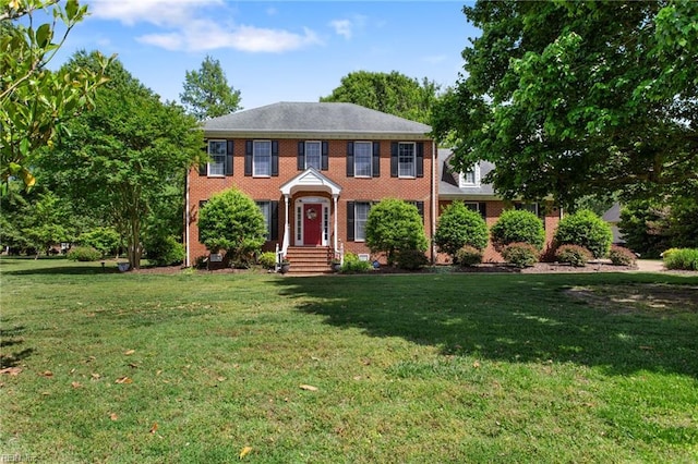 colonial house featuring a front yard and brick siding