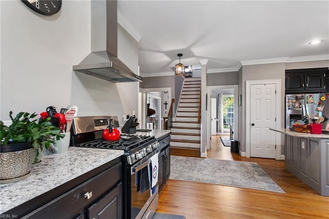 kitchen with appliances with stainless steel finishes, wall chimney exhaust hood, light wood finished floors, ornamental molding, and baseboards