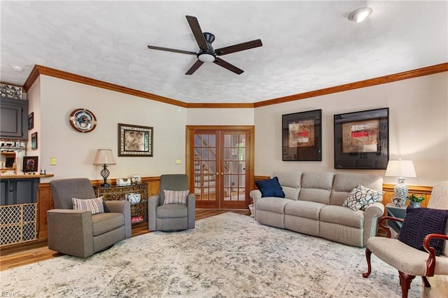 living room with wood finished floors, french doors, a ceiling fan, wainscoting, and ornamental molding